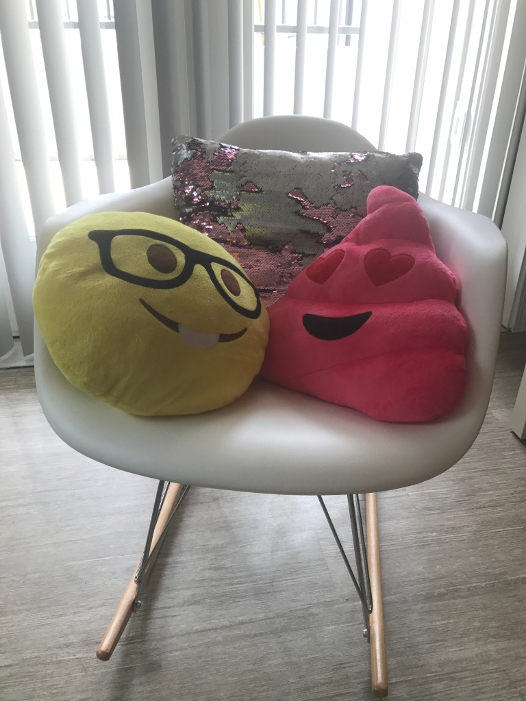 Reversible sequin pillow along with Emoji pillows on display